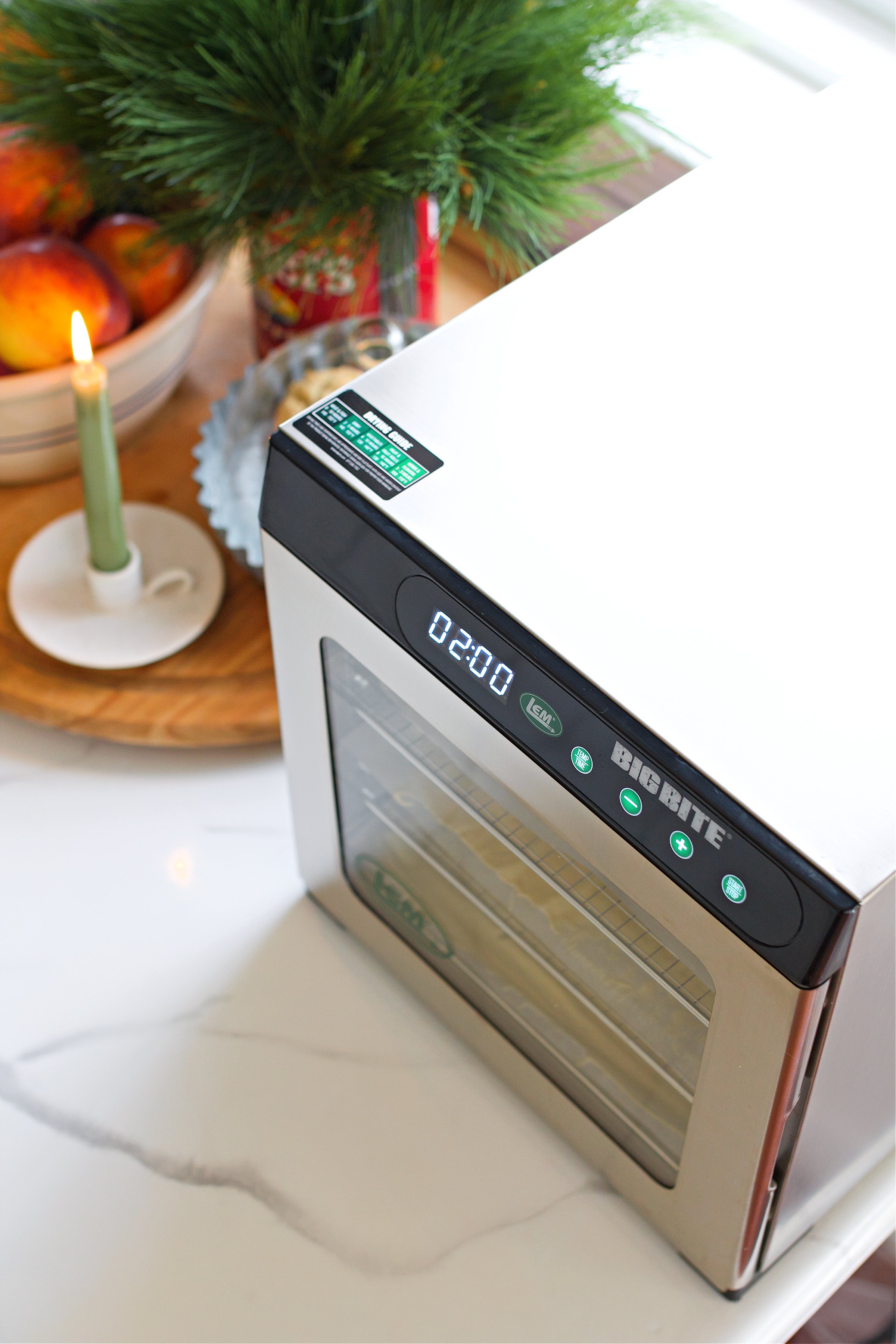 Dehydrator on counter by candle with orange slices inside. 