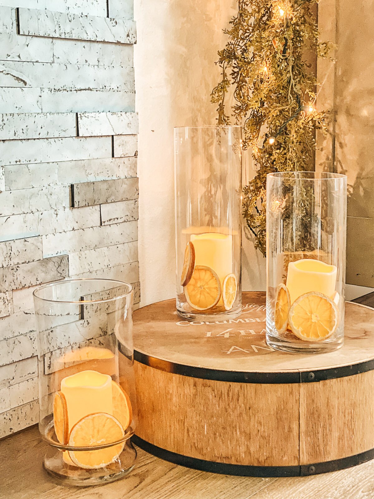 Three glass candle stands with faux candles in them and dried orange slices stuffed in around them.