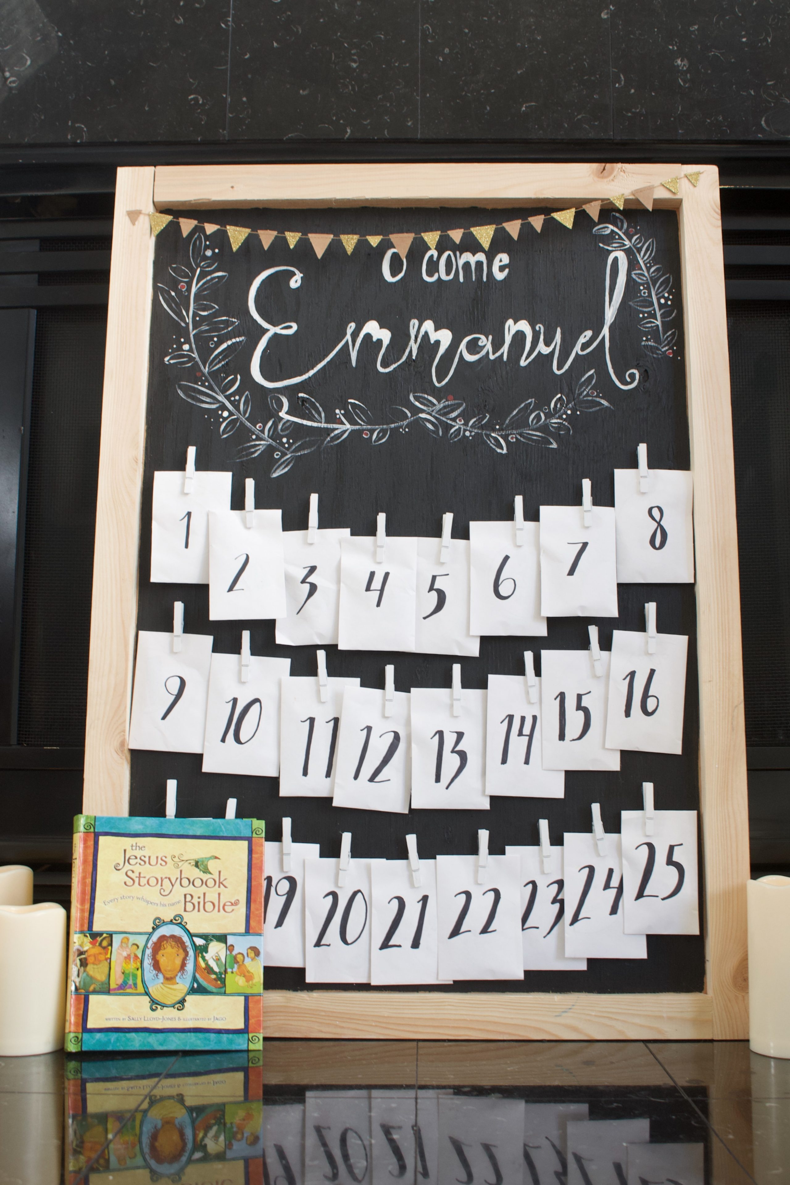 Photo of the chalkboard looking advent calendar that has mini enveloped clipped to it by min clothespins.