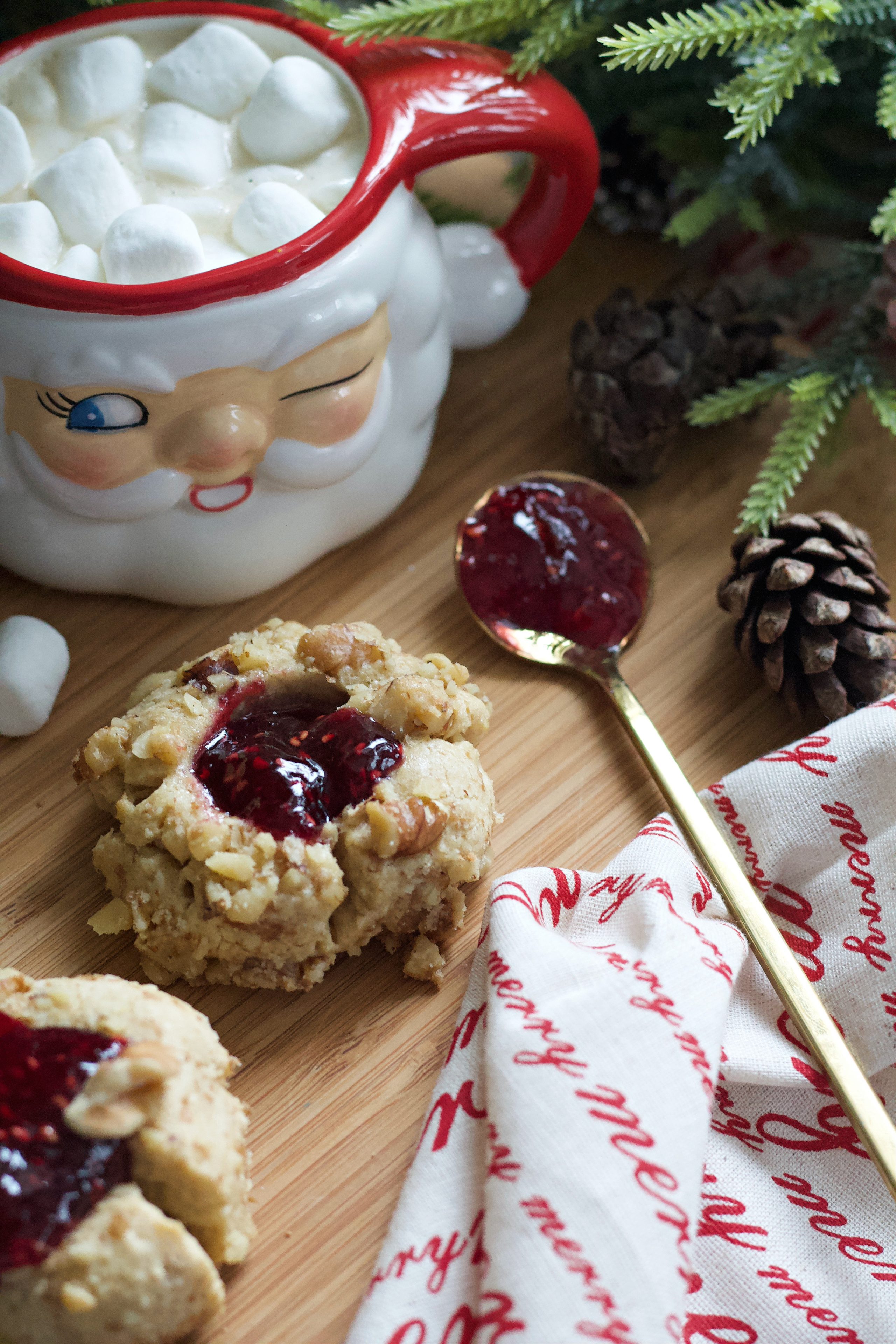 Two thumbprint cookies on counter with cup of hot cocoa.