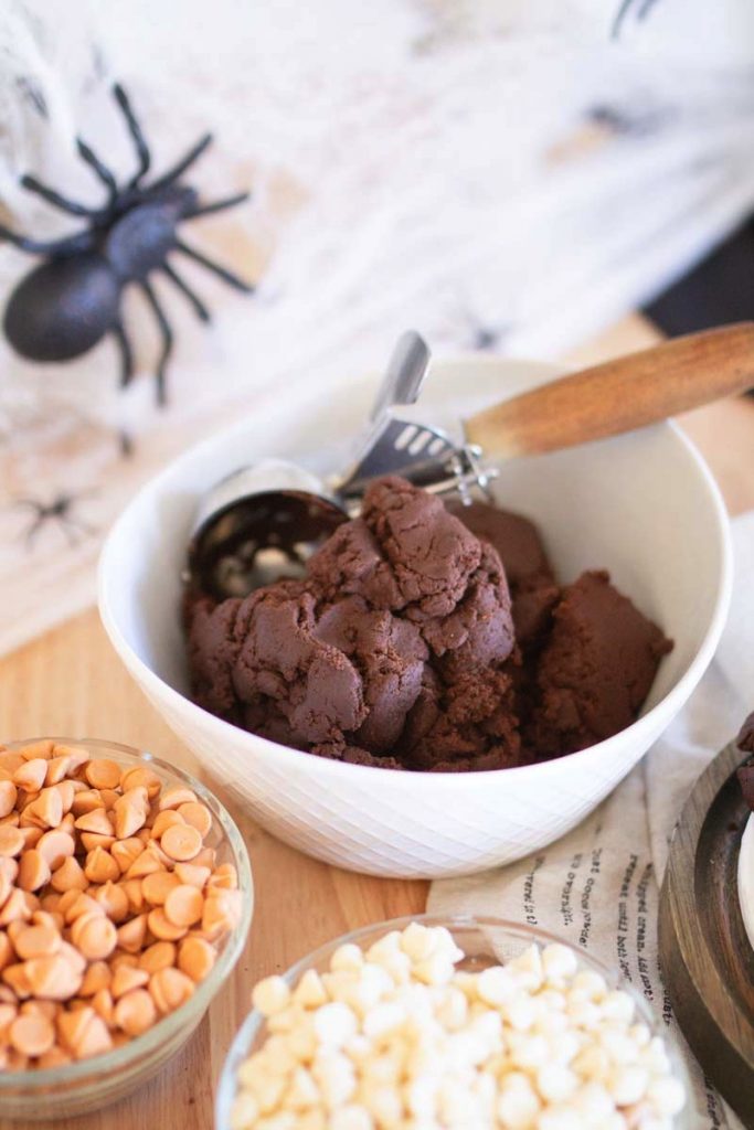 Bowl of chocolate cookie dough with halloween decor around it.