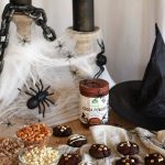 Chocolate cookies in a spooky Halloween backdrop with candles, webbing, spiders, and a witch hat.