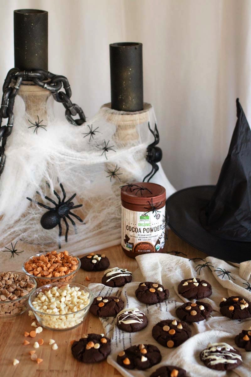 Chocolate cookies in a spooky Halloween backdrop with candles, webbing, spiders, and a witch hat.