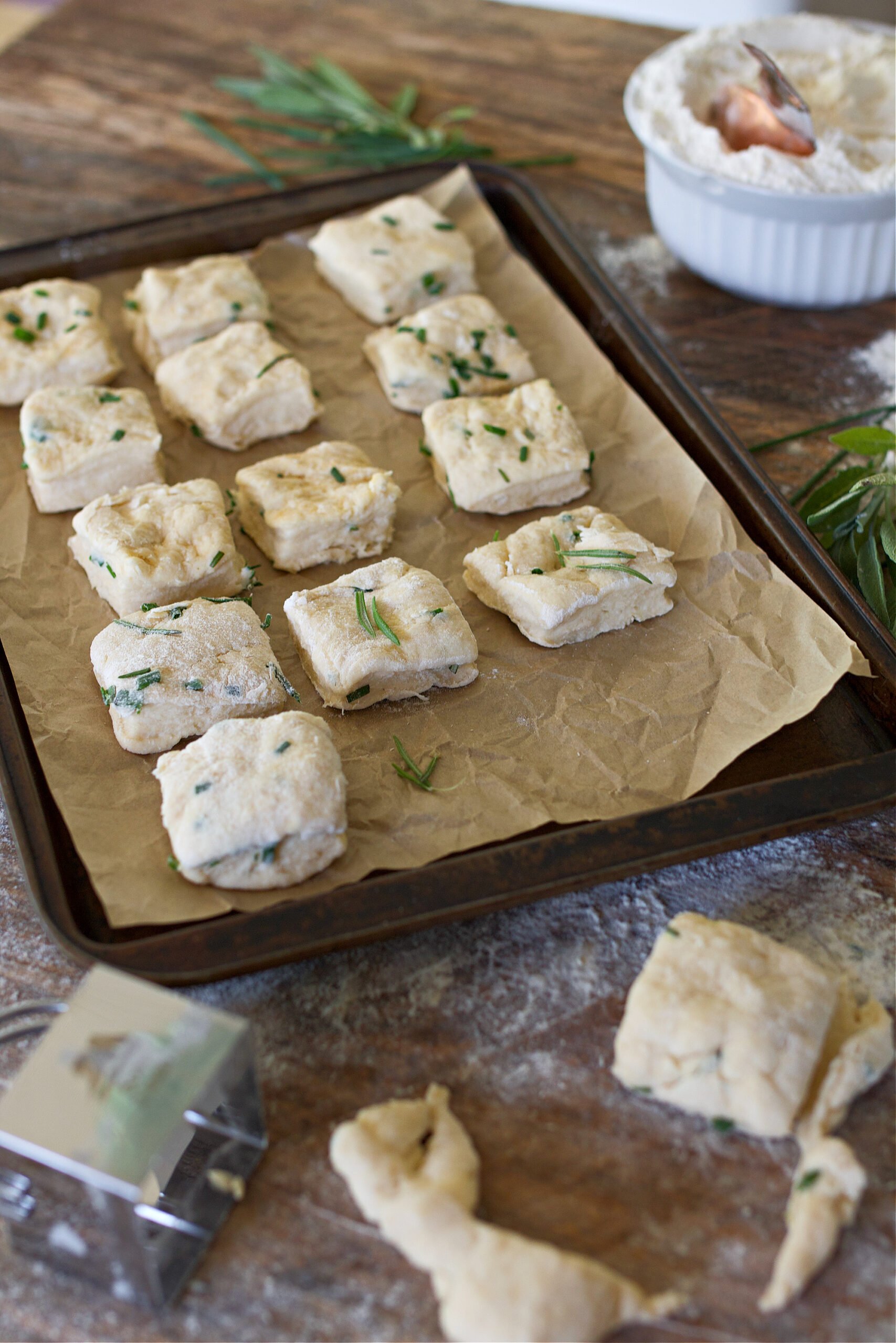 Herbed biscuits on a cooking sheet before being baked.