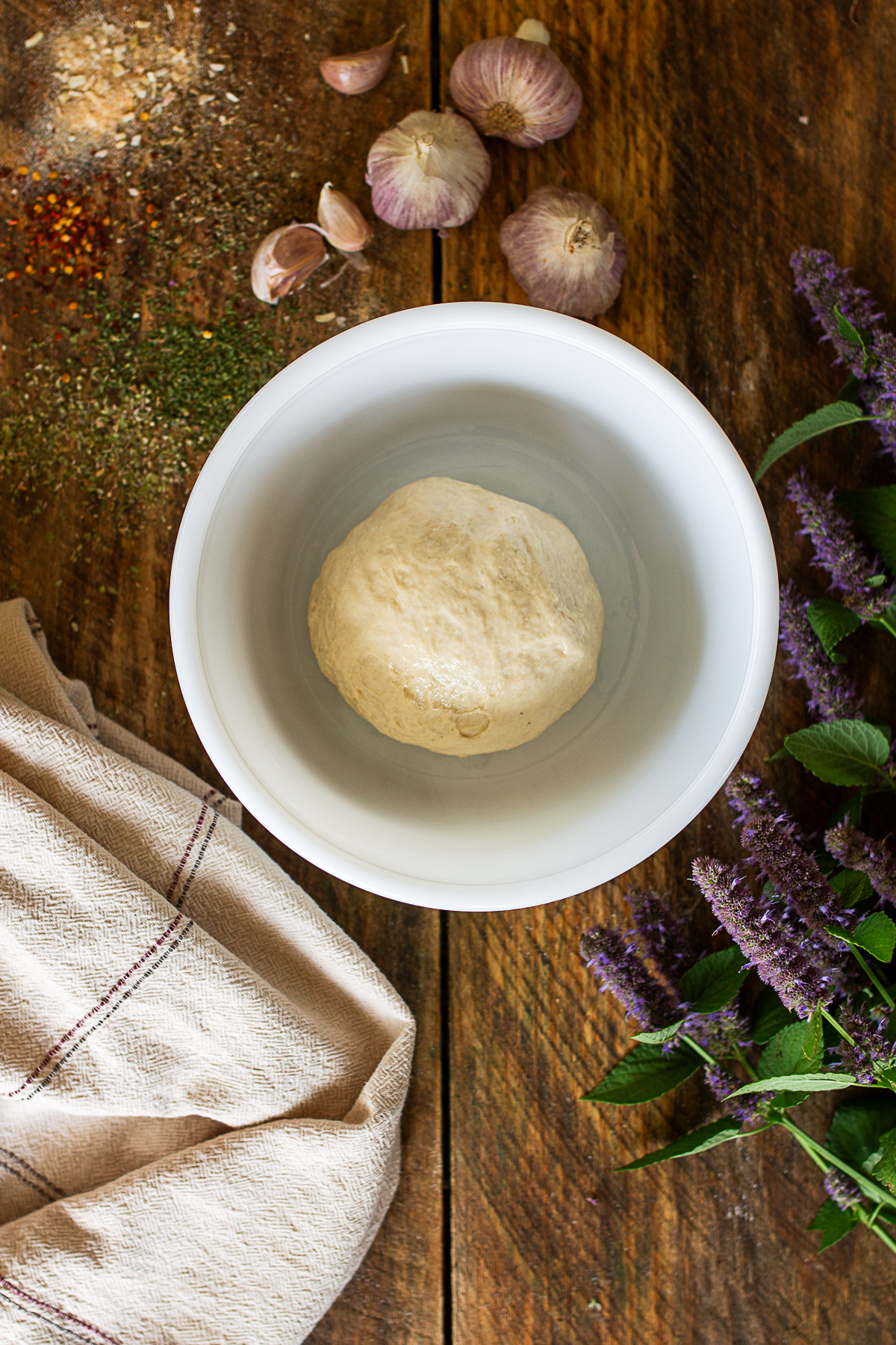 Roll of pizza dough in white glass bowl before rise.