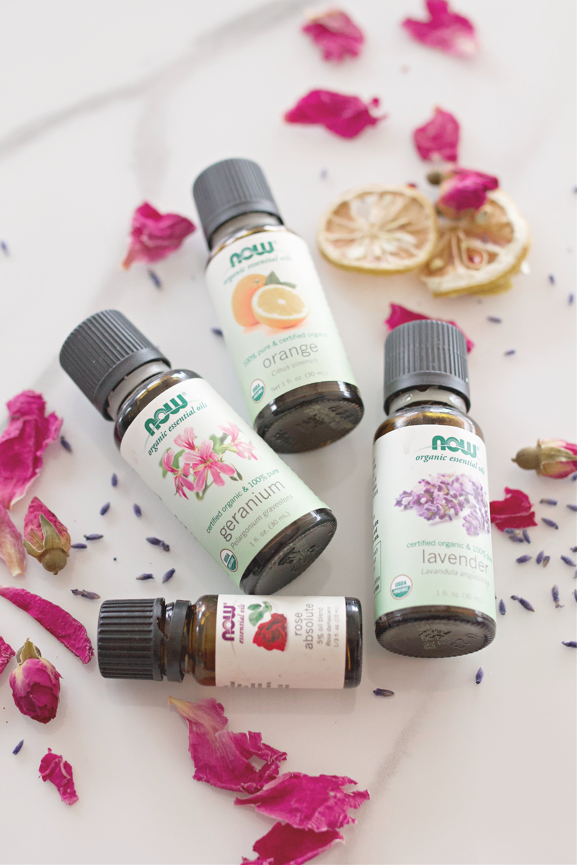 Bottles of essential oils sitting on a counter with potpourri around them. 