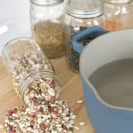 beans in mason jars and a stock pot of water on a wooden counter.