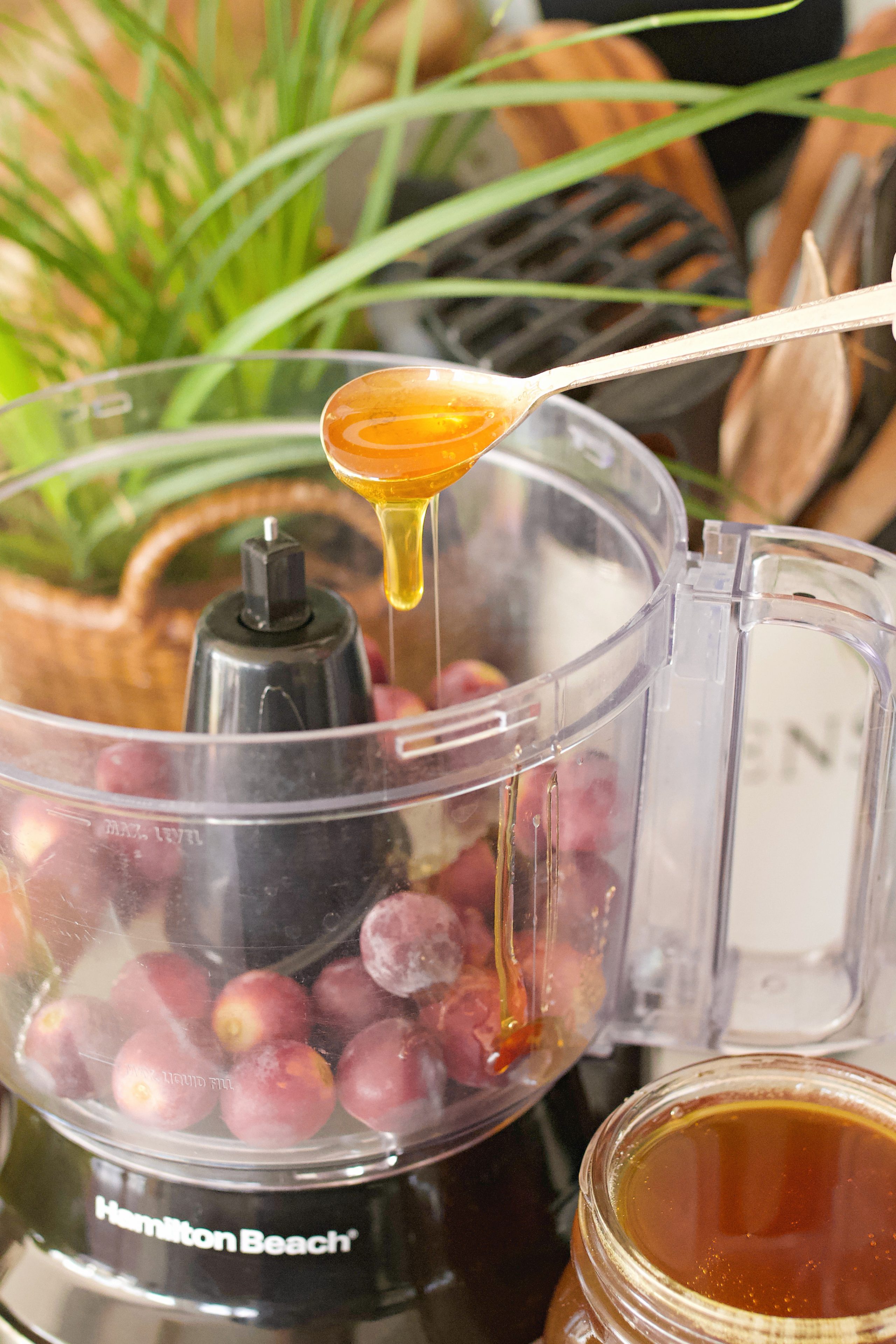 Drizzling honey into the food processor with the frozen grapes.