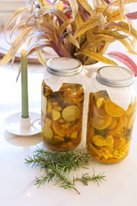 two half gallons of fire cider on a counter next to a plant and candle