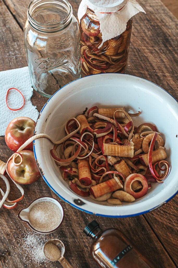 Apple pieces sitting in a bowl on the counter with half gallon jars and sugar.
