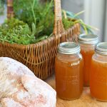 chicken simmering in pot with herbs to cook for bone broth.