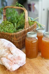 chicken simmering in pot with herbs to cook for bone broth.