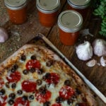 Pizza beside cans of pizza sauce.