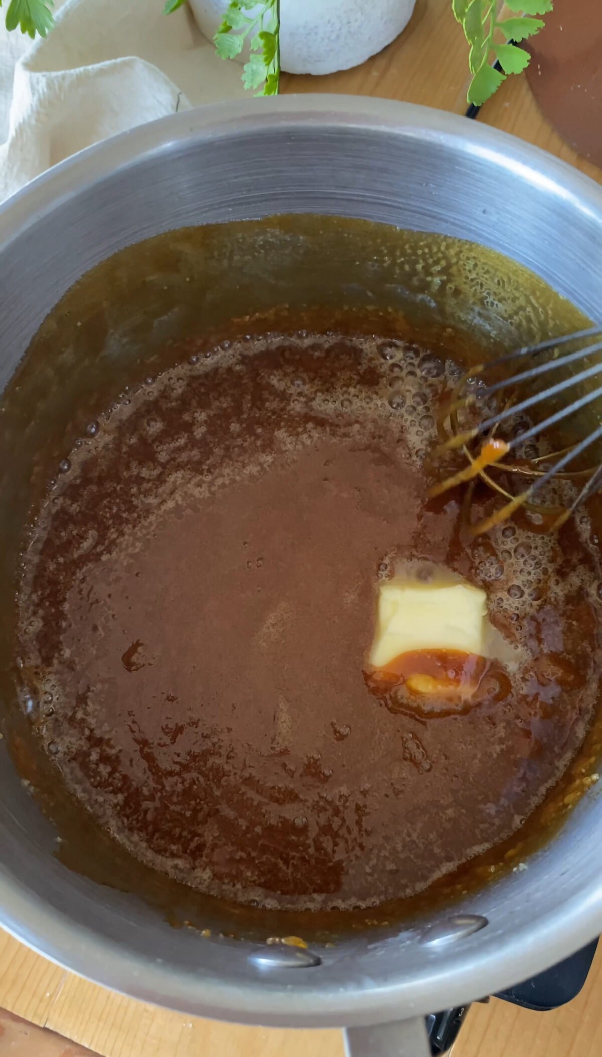 Adding butter to the saucepan of melted sugar.