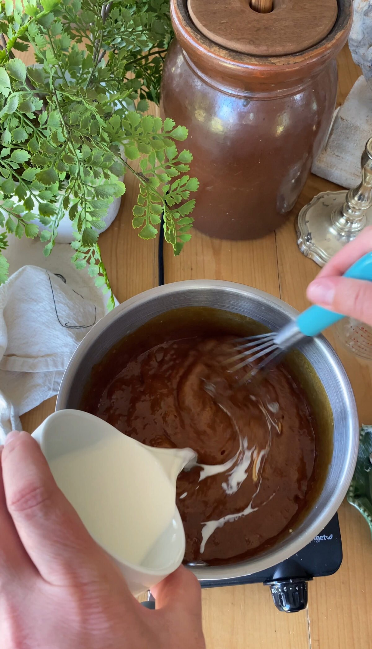 Pouring Milk into caramel mixture in saucepan.