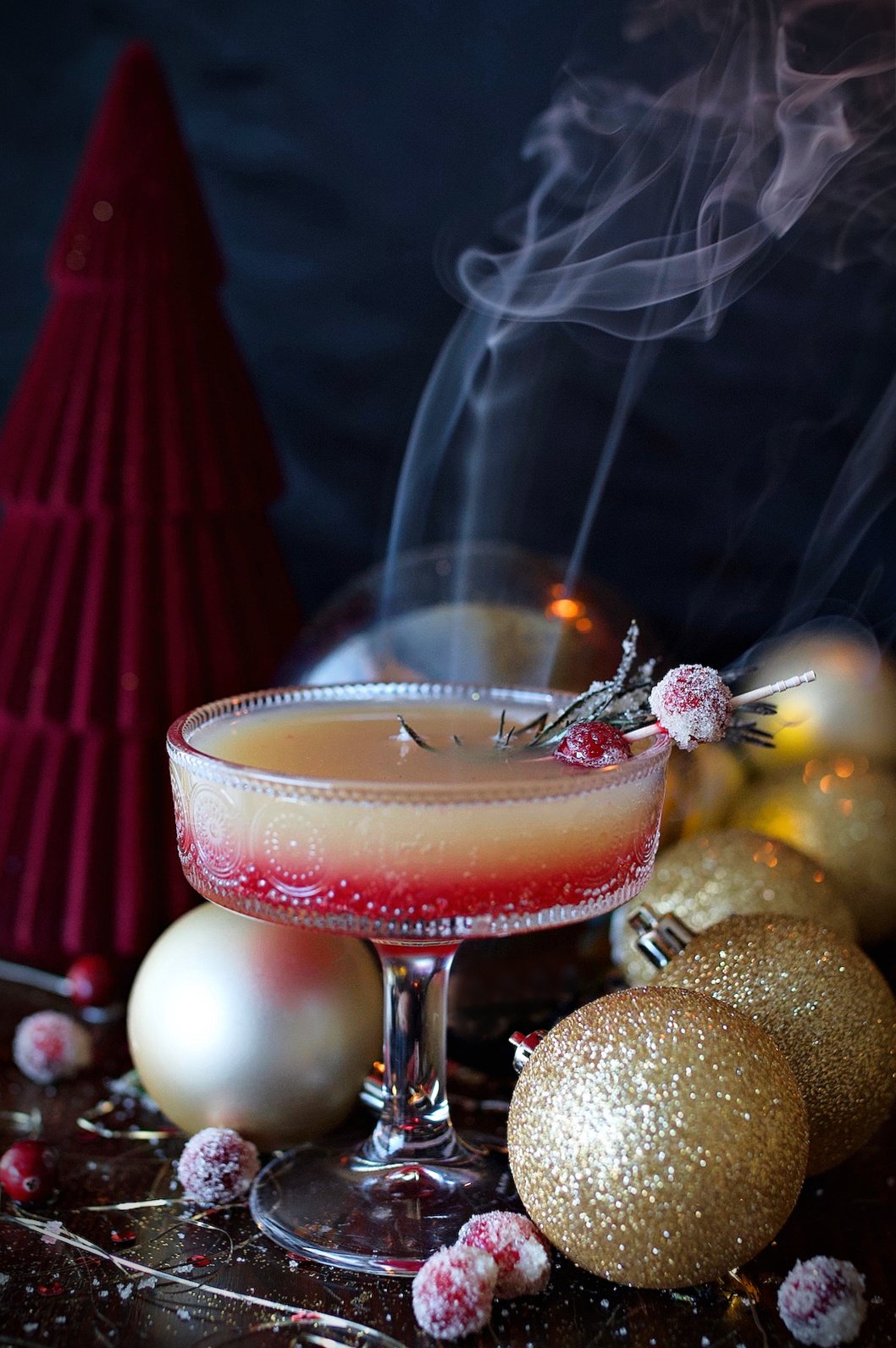 Cranberry spritzer drink on counter with rosemary and cranberry garnish. 