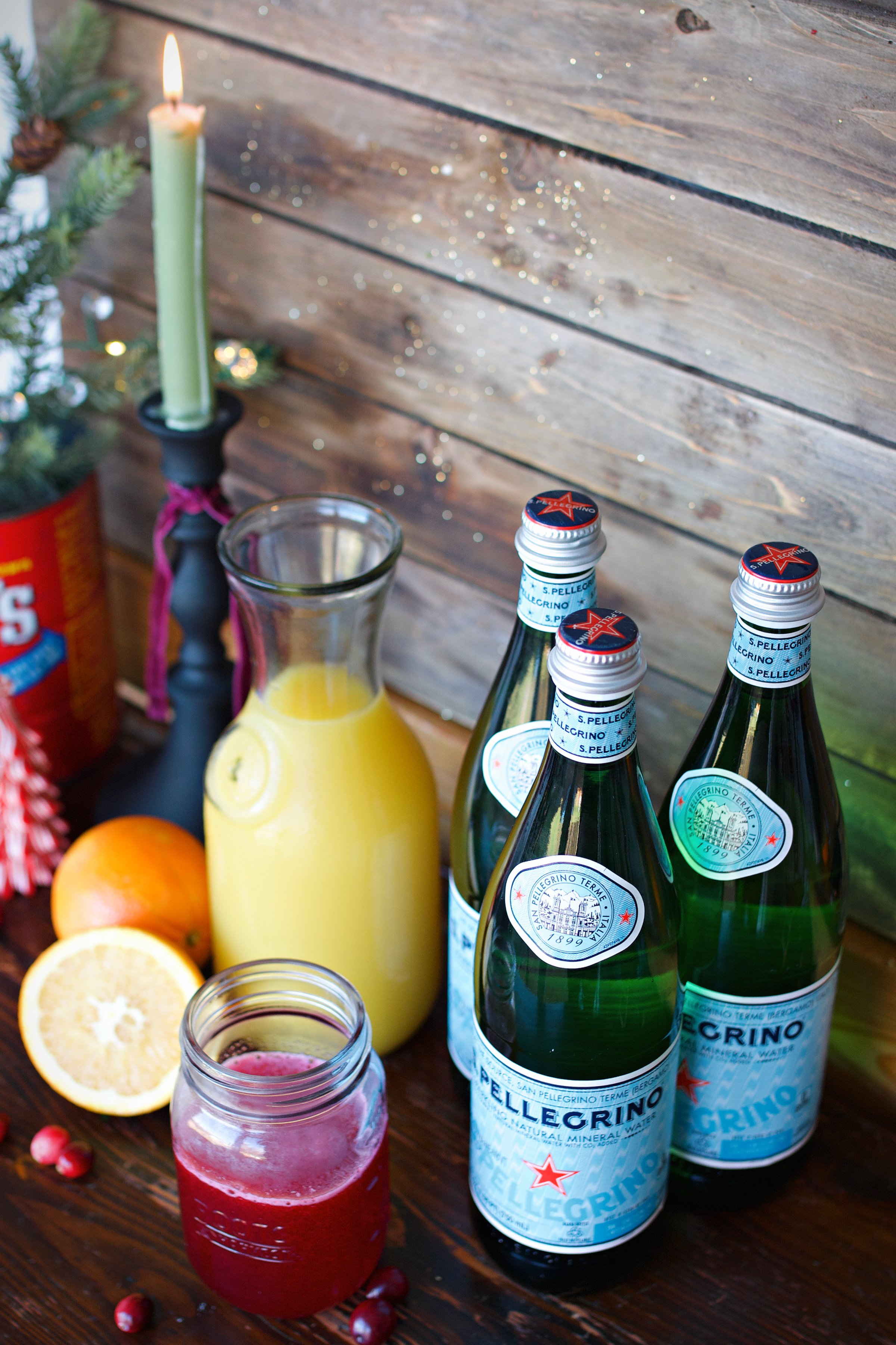 Ingredients for orange cranberry spritzer on the counter. Sparkling water, orange juice, and cranberry juice. 