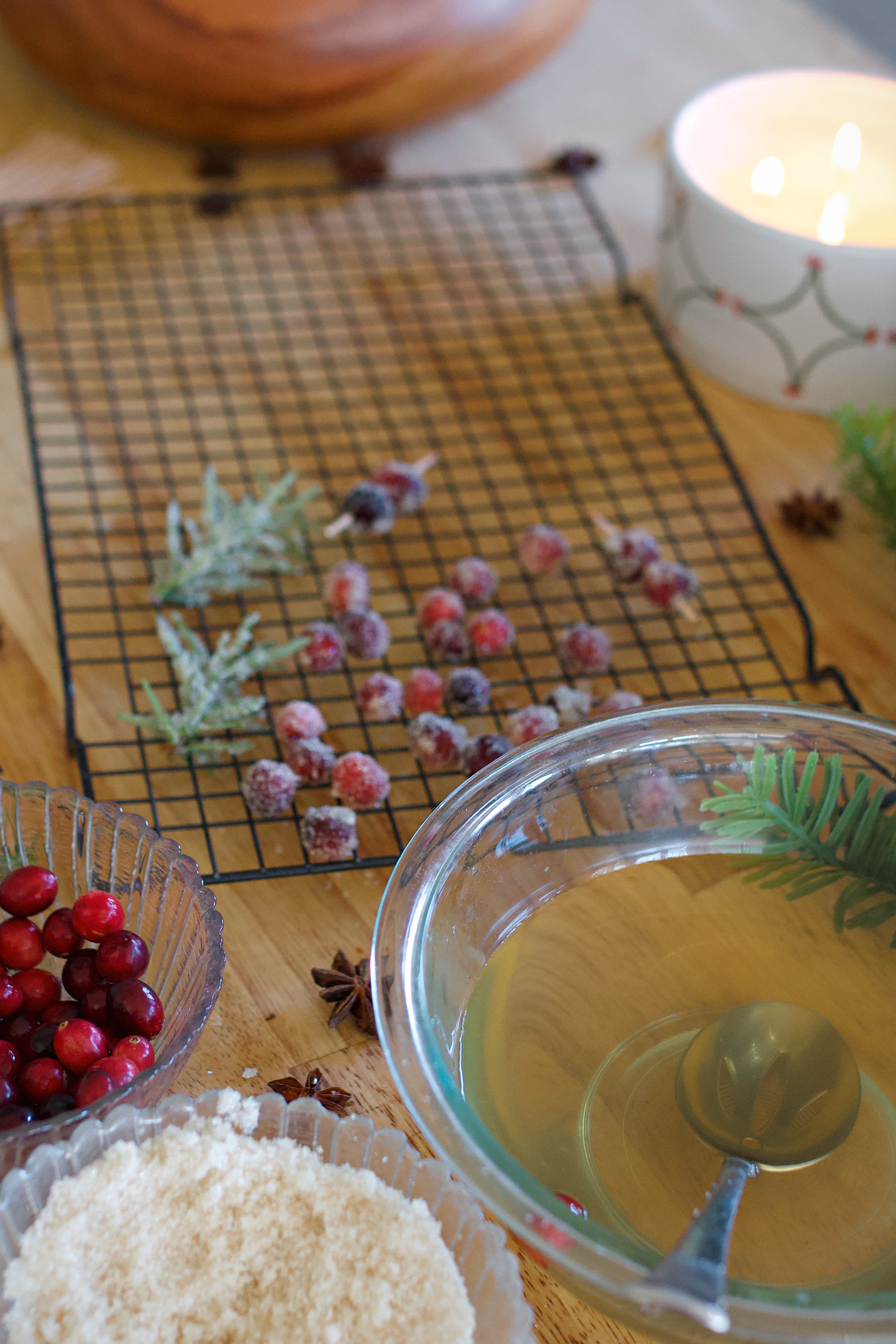 Ingredients on counter for sugared cranberries and rosemary plus finished sugared items on rack. 