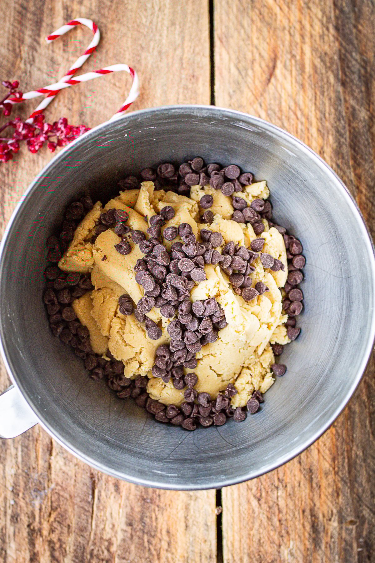 Biscotti dough in mixing bowl with chocolate pieces on tip ready to be folded in.