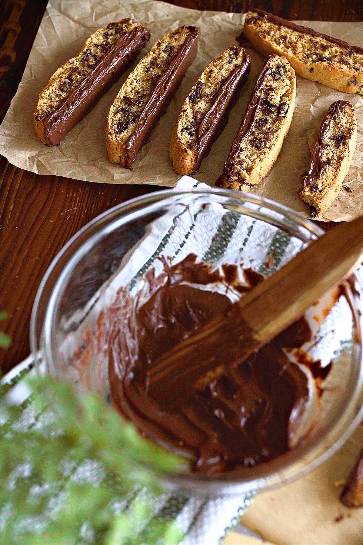 Adding melted chocolate to the bottoms of each biscotti. 