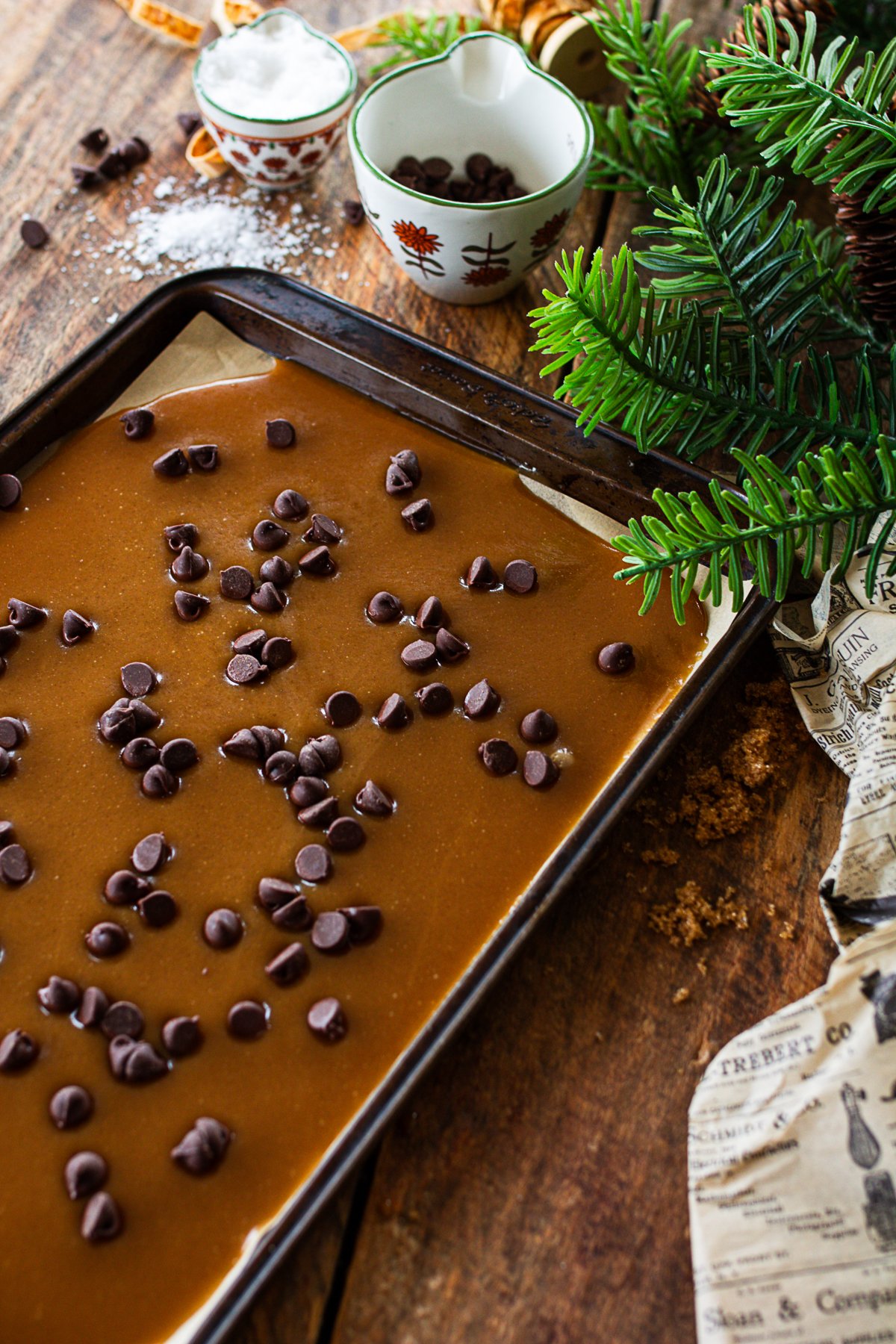 toffee with chocolate chips melting on top in preparation to spread them into a thin chocolate layer.