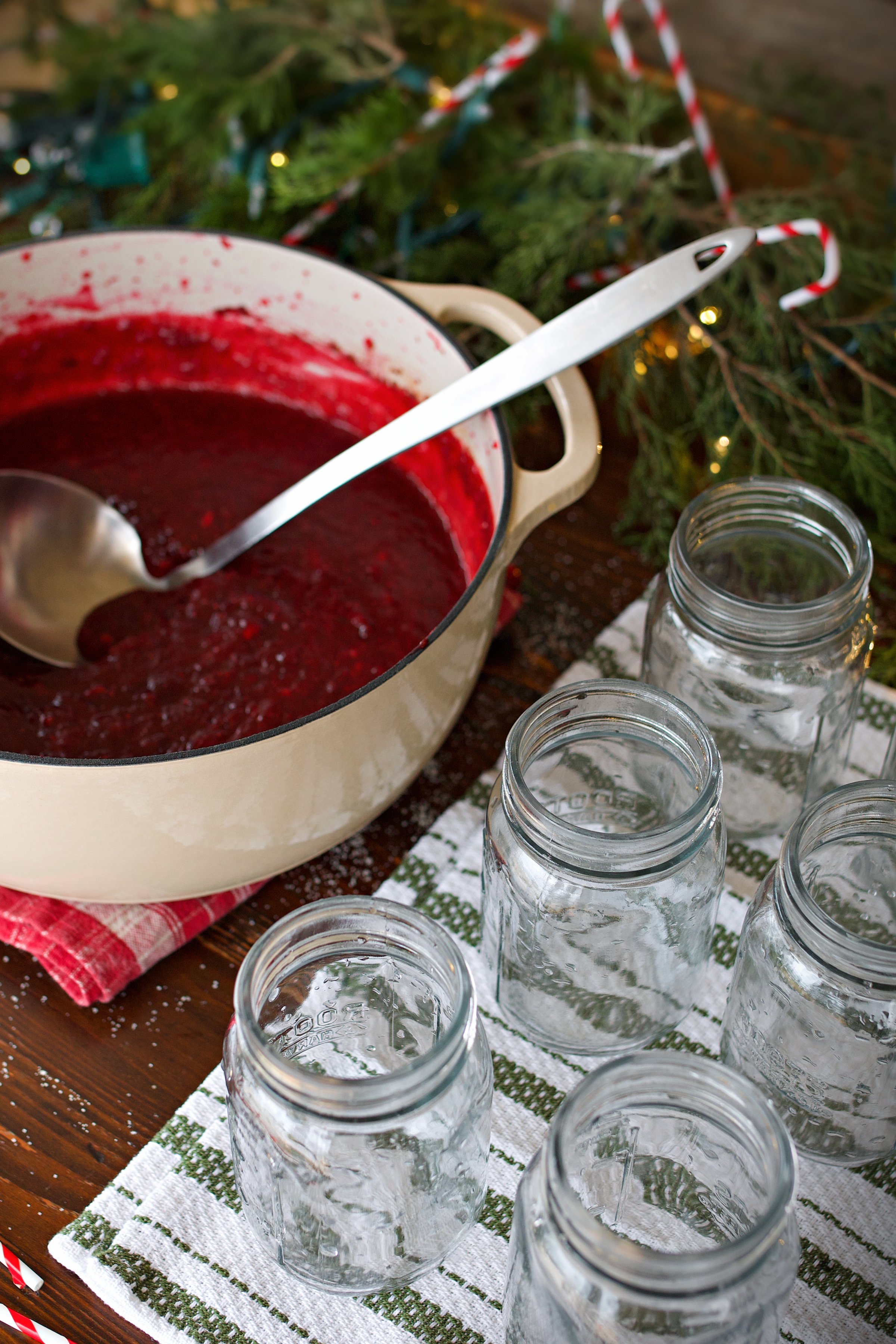 spiced cranberry jam in stockpot with canning jars clean and ready beside it.
