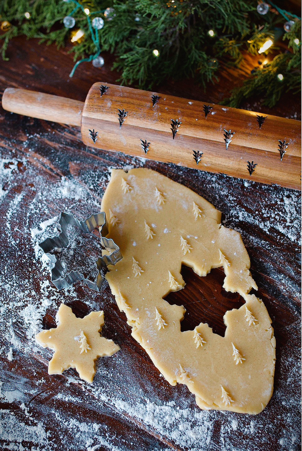 Rolling pin on counter beside rolled dough that's being cut out with star cookie cutter.
