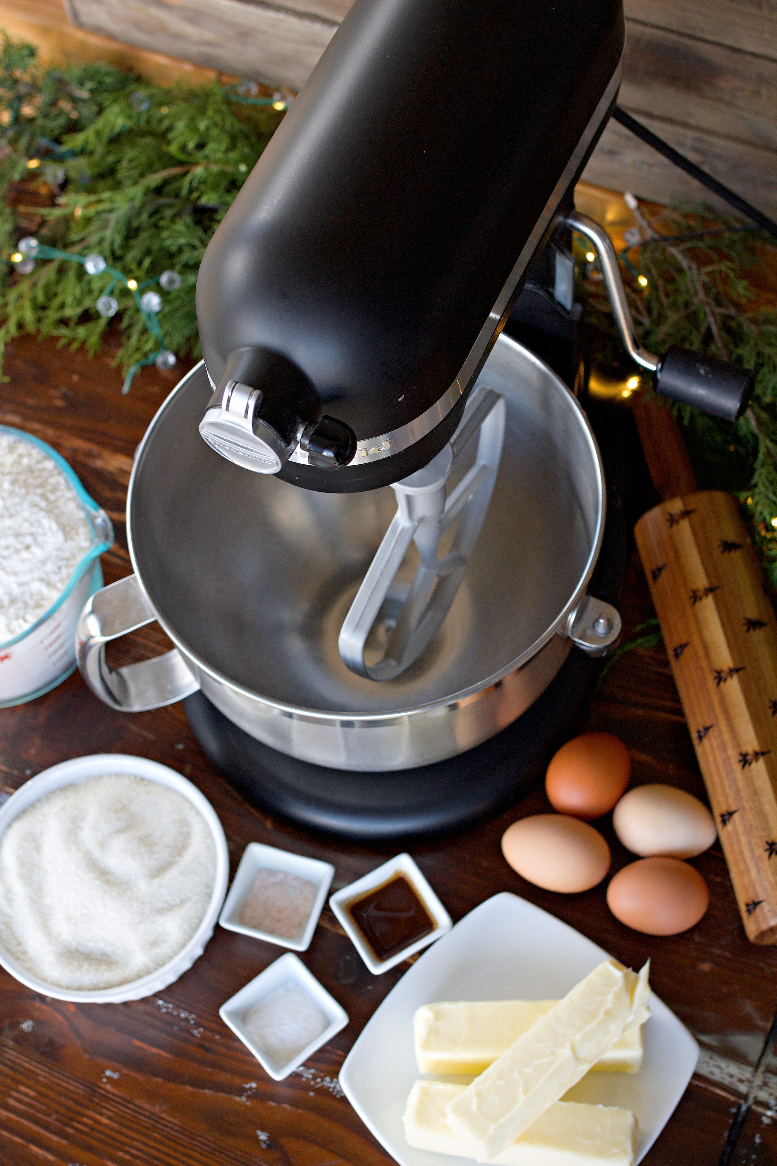 Ingredients for cookies on counter beside Kitchen Aid mixer. Eggs, sugar, vanilla, butter, baking powder, flour, and salt.