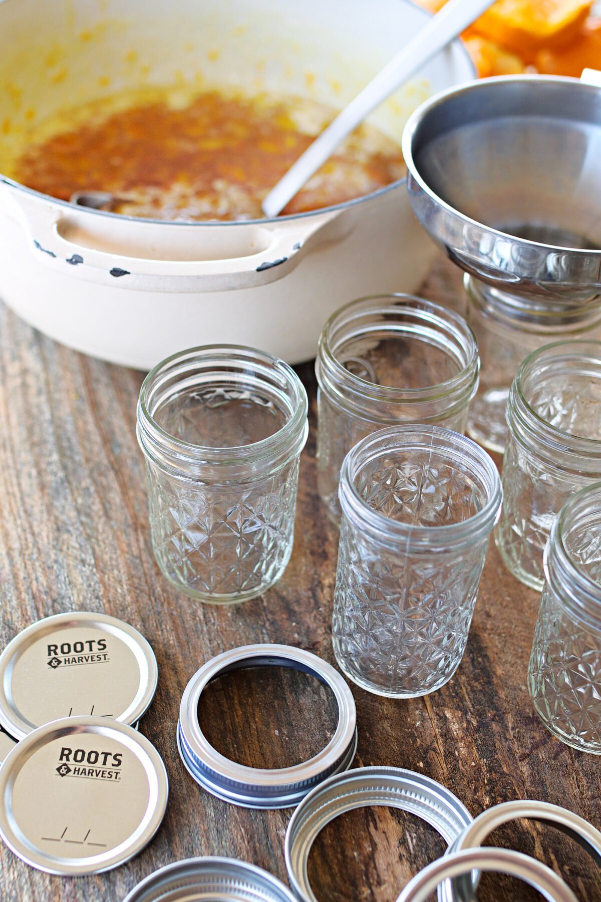 jam jars on counter beside stockpot of marmalade ready to be filled. 