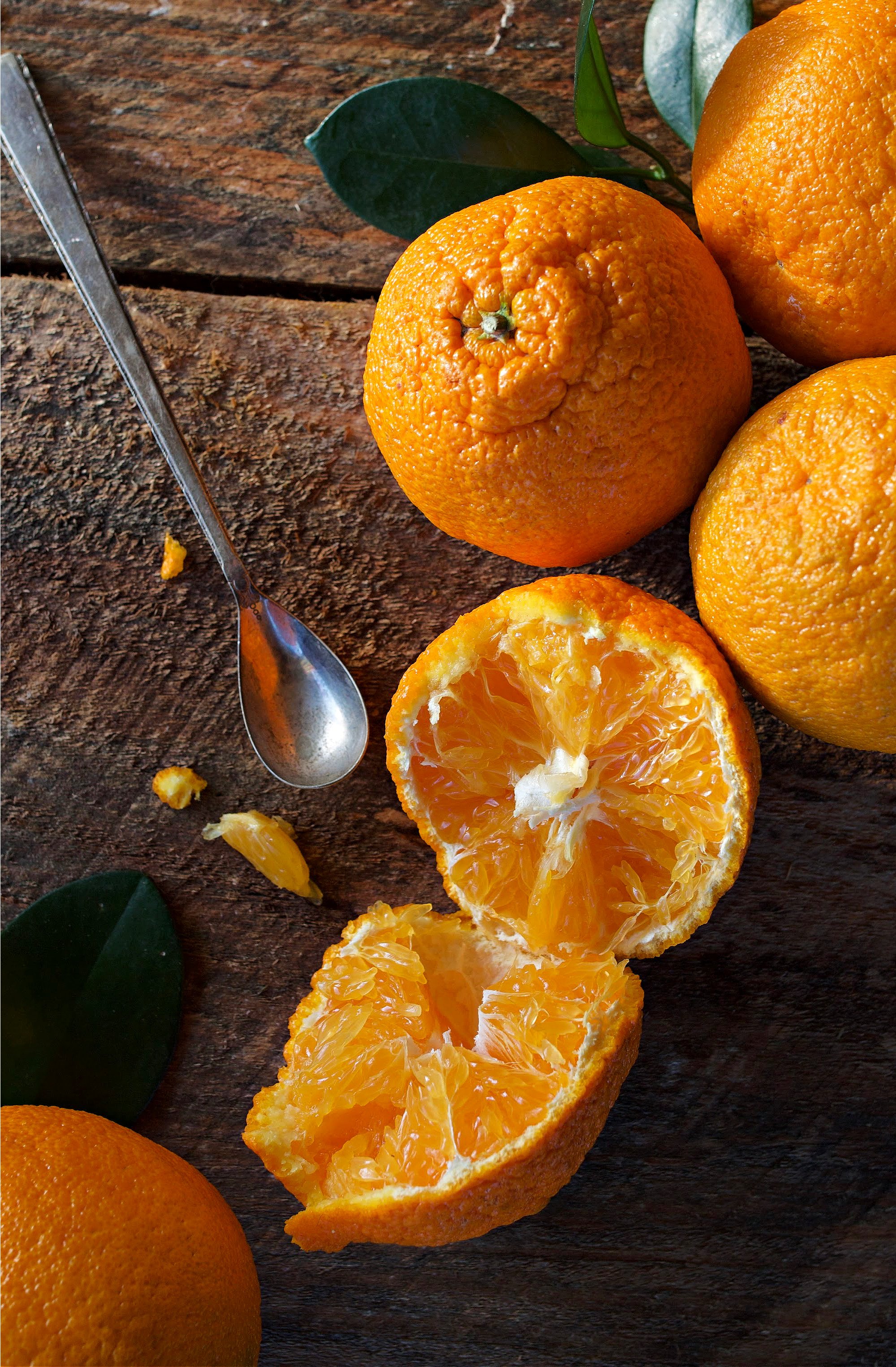 Oranges on counter with one open and a spoon near it. 