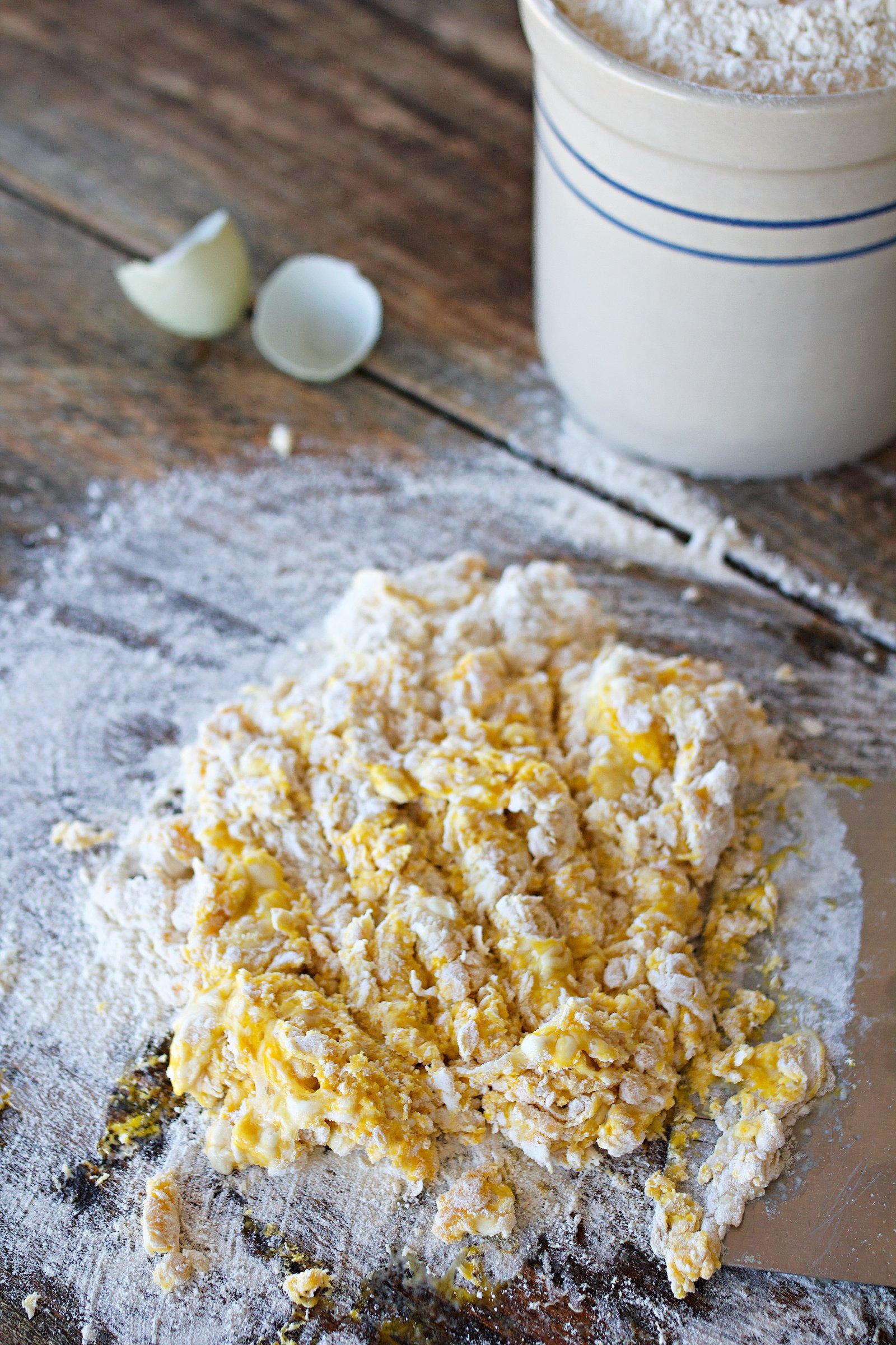 Eggs and flour for noodles being mixed on counter.