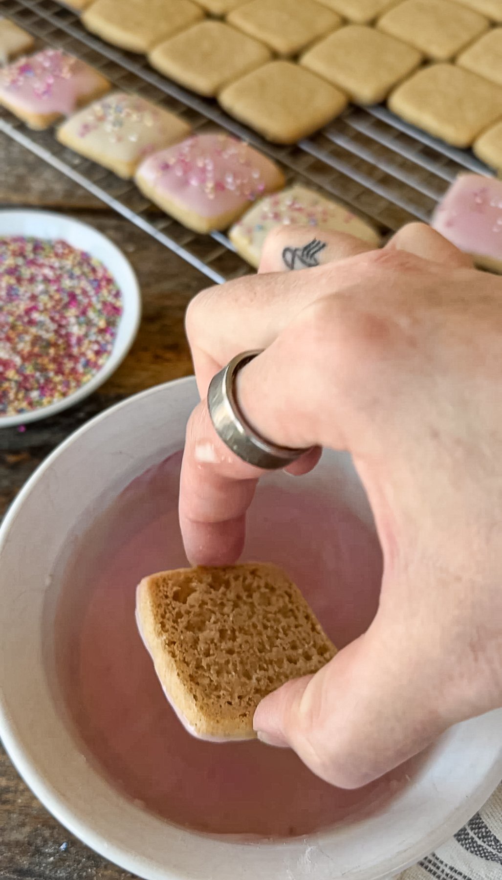 Dipping cookies into pink frosting. 