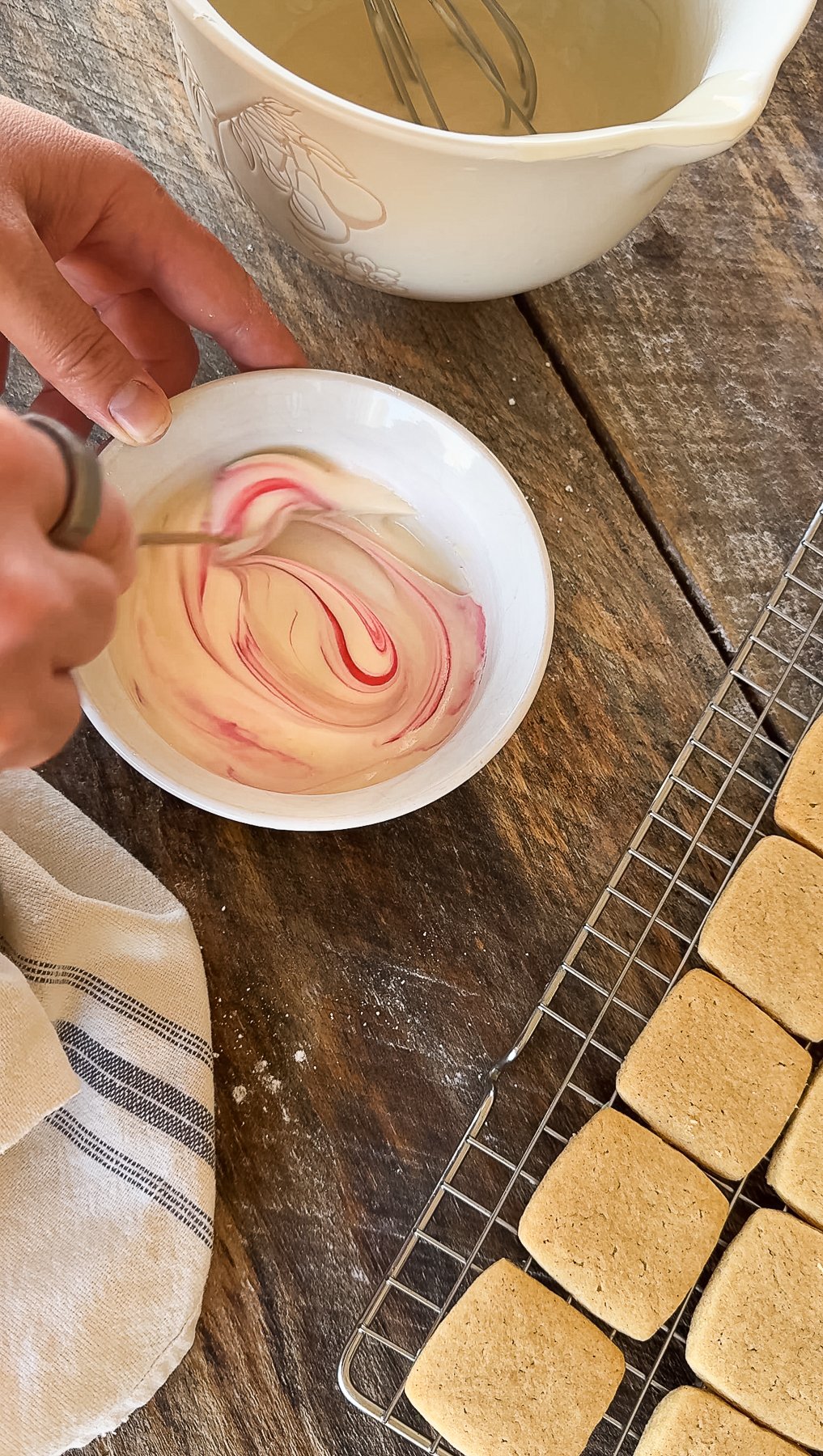 Mixing pink food coloring into frosting. 