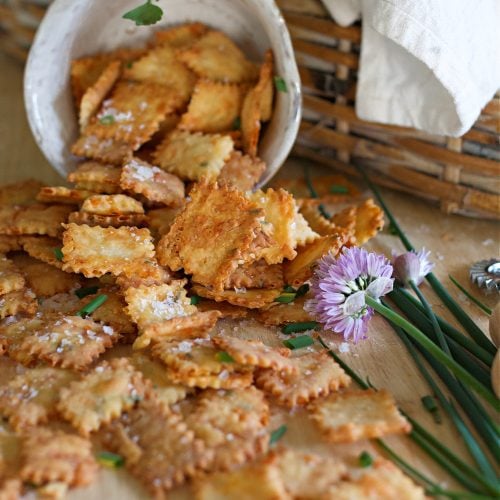 Homemade Cheez its pouring out of ceramic bowl onto counter.