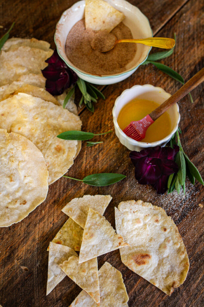 tortillas being cut up to turn into chips with whip cream and jam dip beside them.
