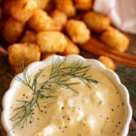 tartar sauce front and center with tater tots next to it.