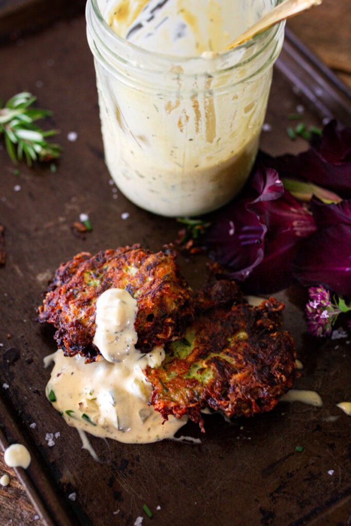 Zucchini fritters with tartar sauce on pan ready to eat.