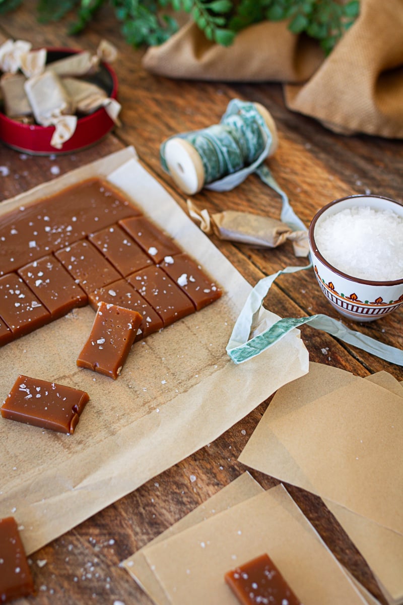 fresh out of the oven caramel candies that have been cut into pieces topped with sea salt ready for wrapping.