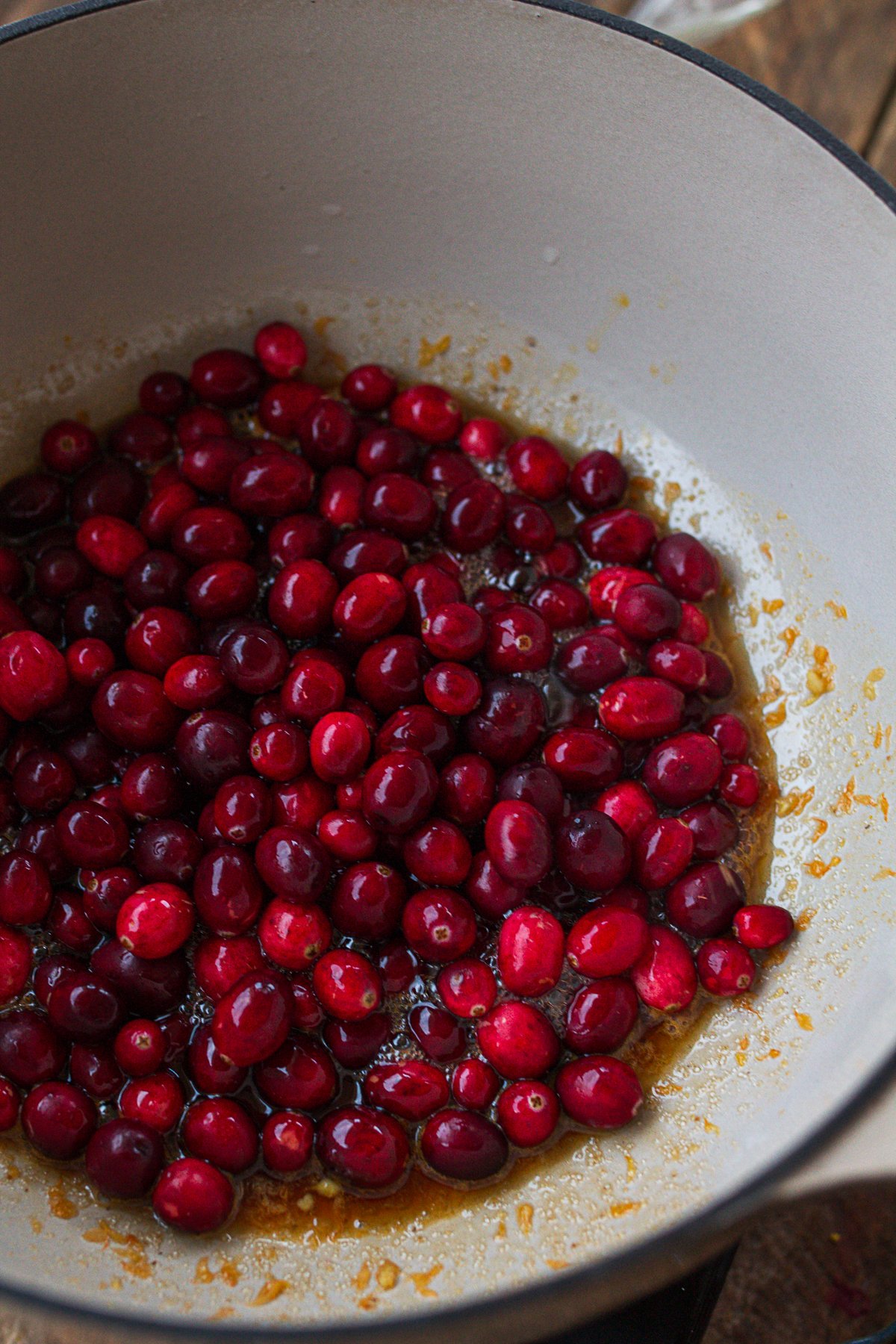 Adding cranberries to pot with melted sugar.