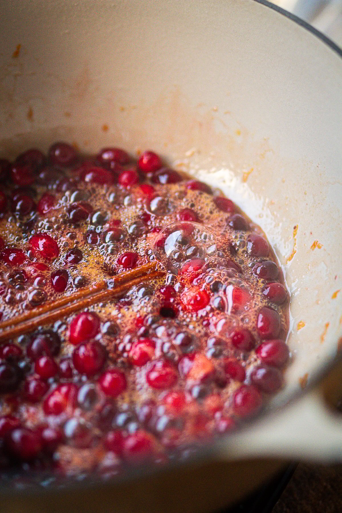 Popping cranberries in pot with cinnamon stick.