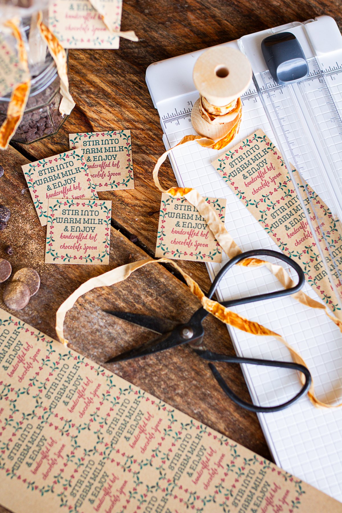 Labels for hot coco spoons being cut out on counter.