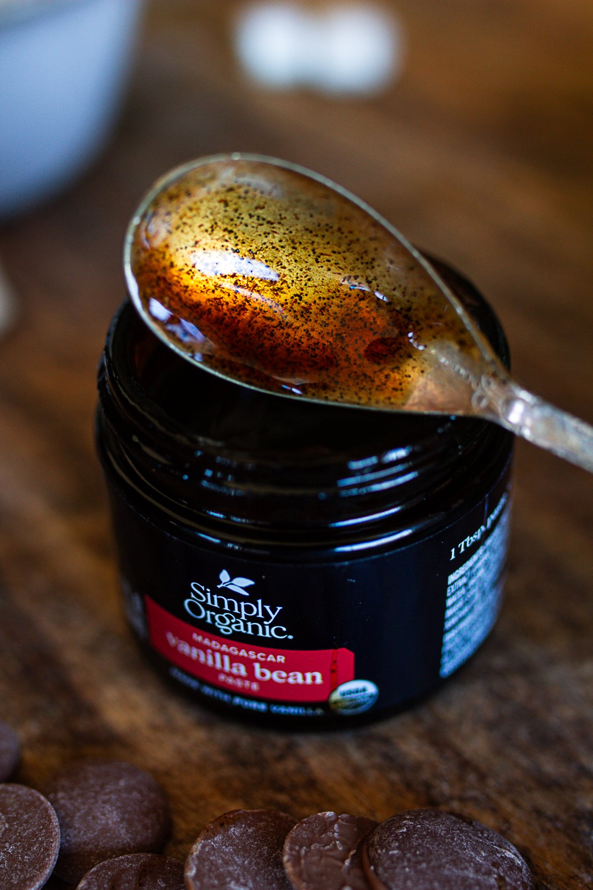 vanilla bean past in glass jar with spoon over top.