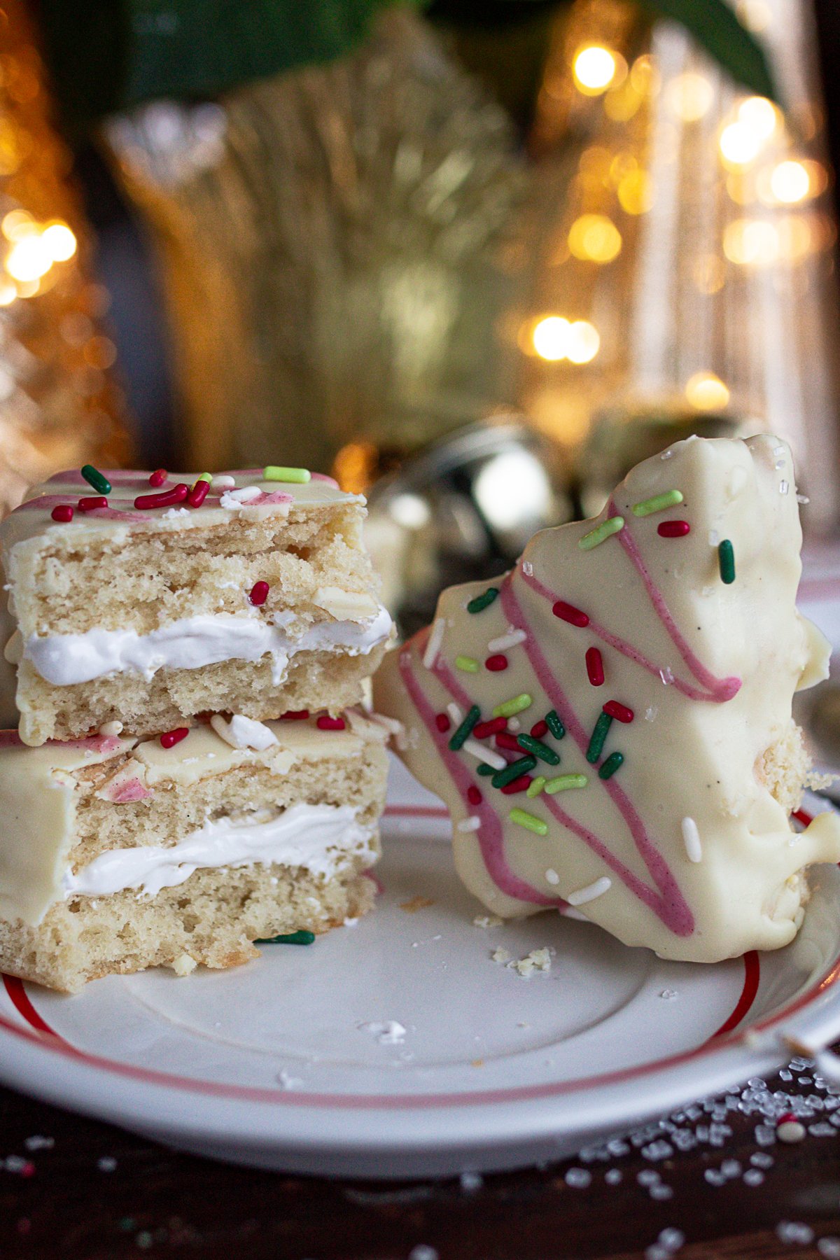 Two Christmas tree cakes on plate. One cut in half and stacked together, the other whole.