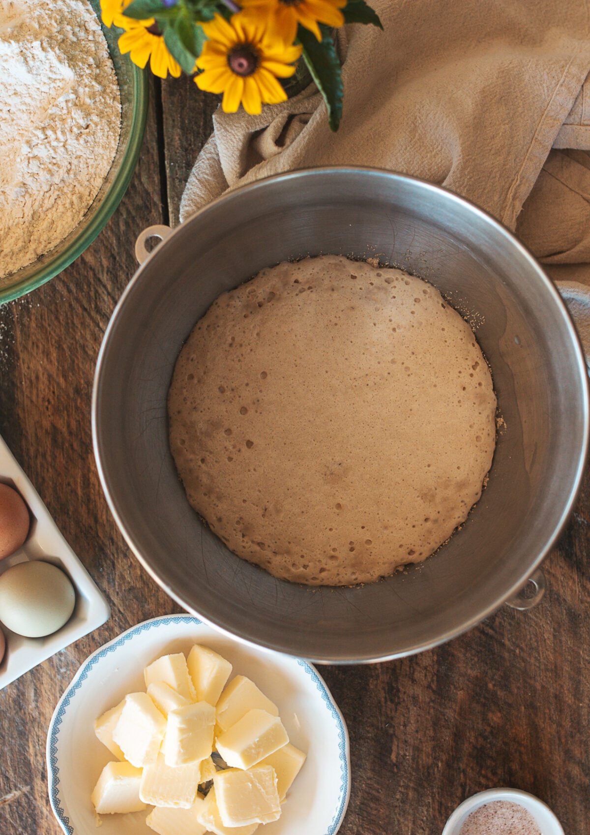 Yeast blooming in warm milk and sugar inside a stand mixer bowl for brioche buns.
