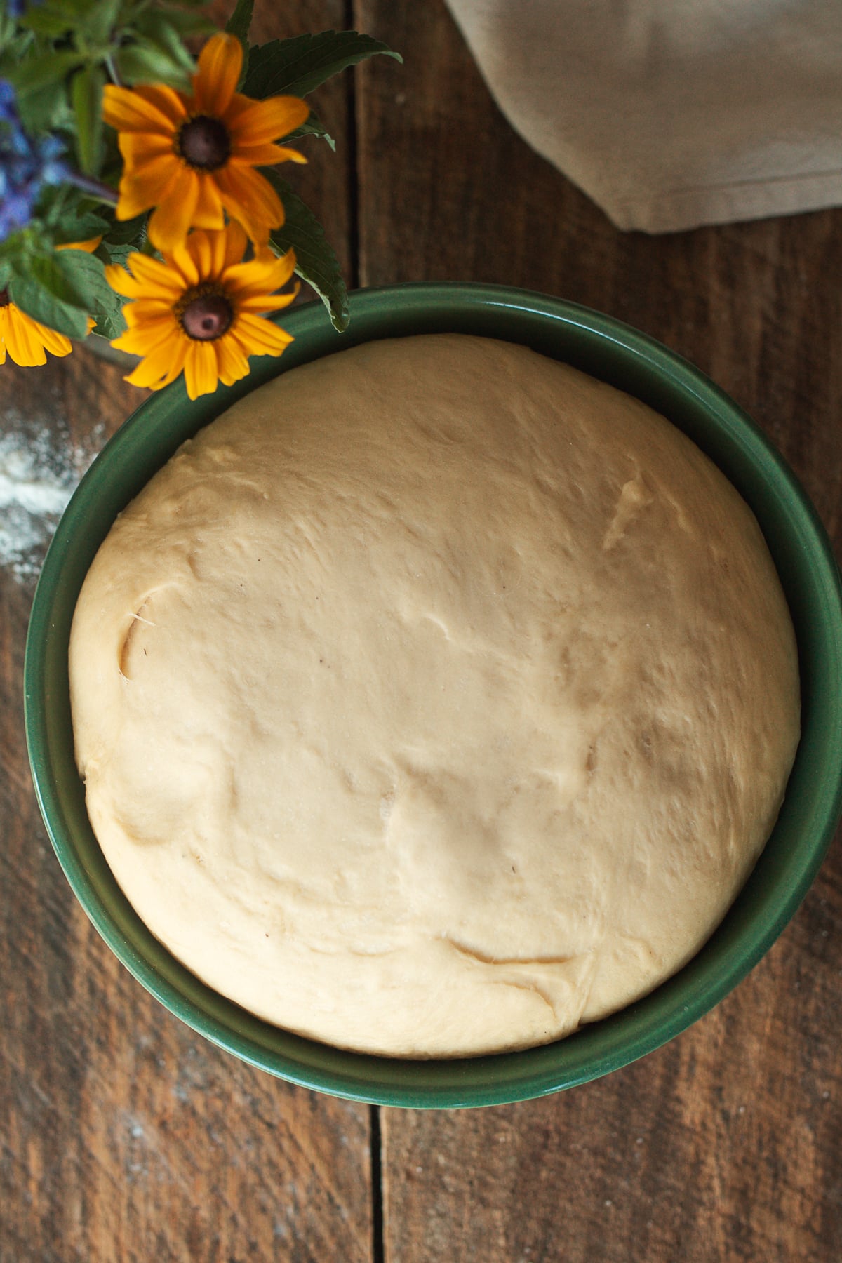 Brioche dough doubled in size after the first rise in a green bowl.