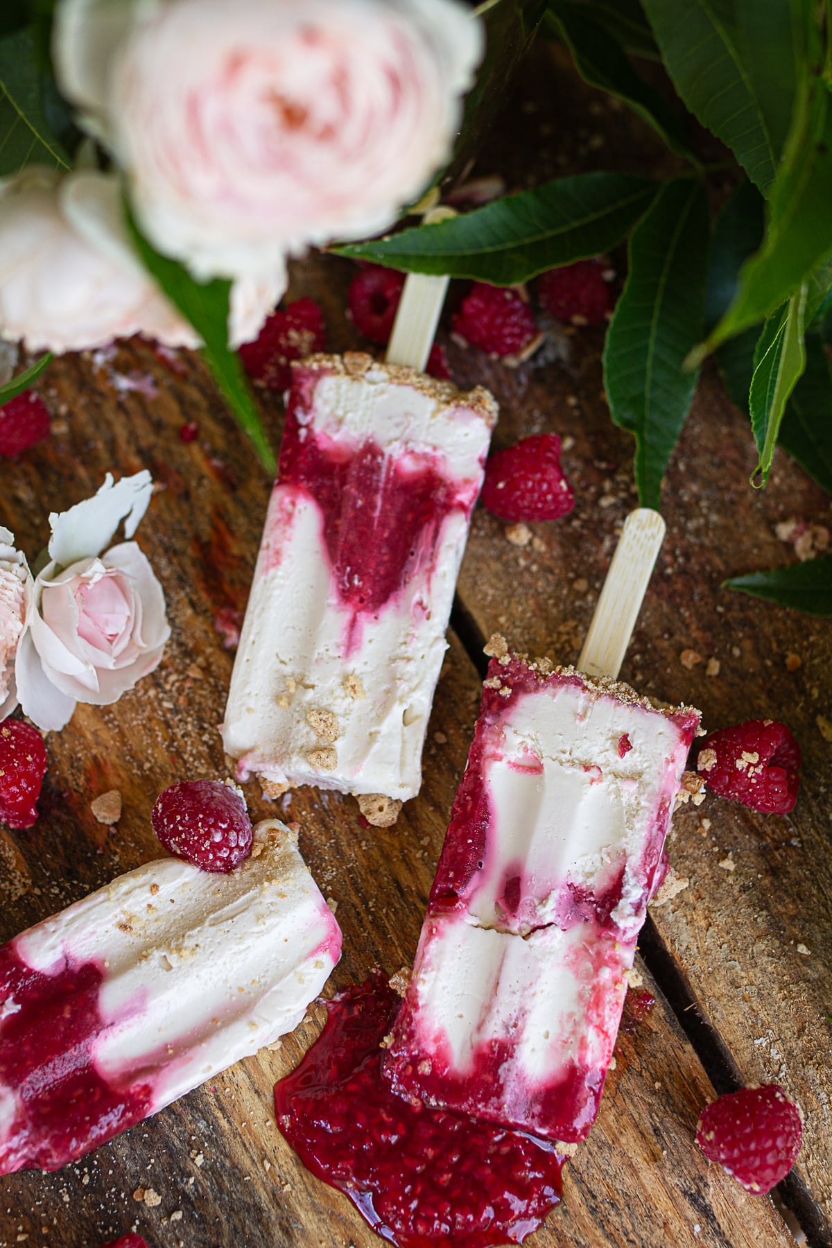 Three unmolded red and white marbled cheesecake popsicles.