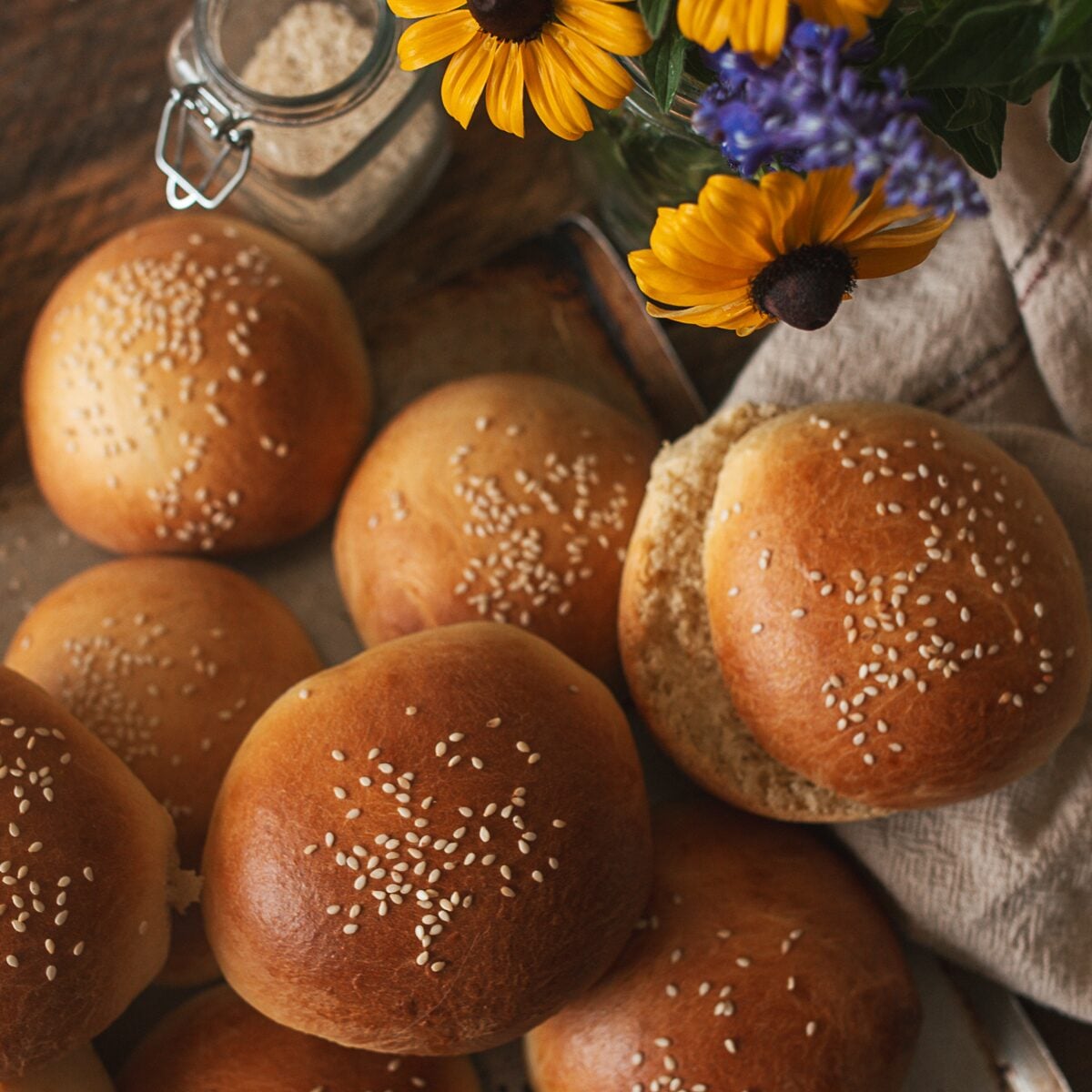 Homemade brioche buns with sesame seeds styled beside fresh flowers