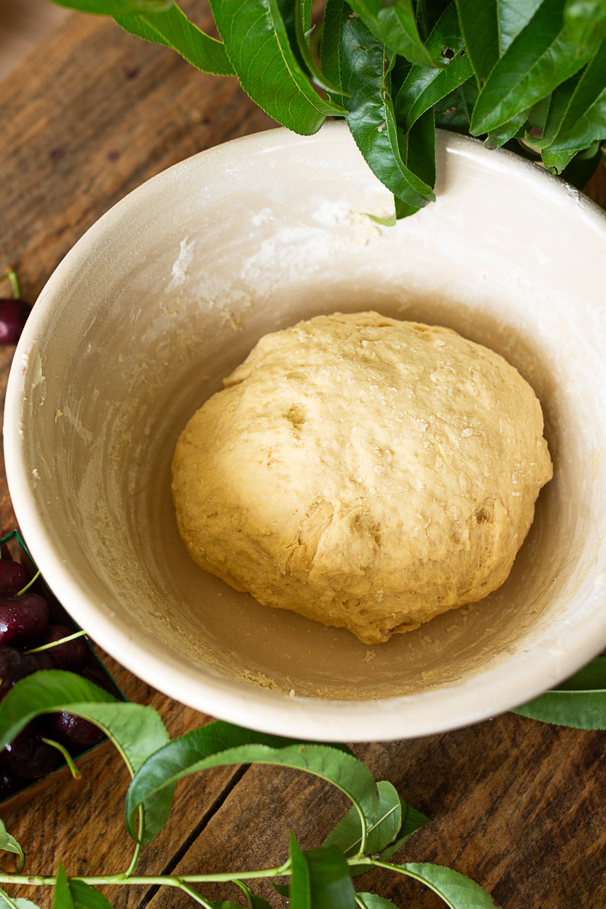 Round ball of sourdough cinnamon roll dough resting in a vintage ceramic mixing bowl