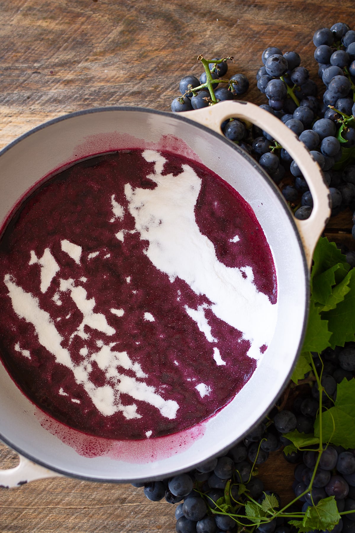 Powdered pectin added to strained Concord grape juice in a pot for homemade grape jelly