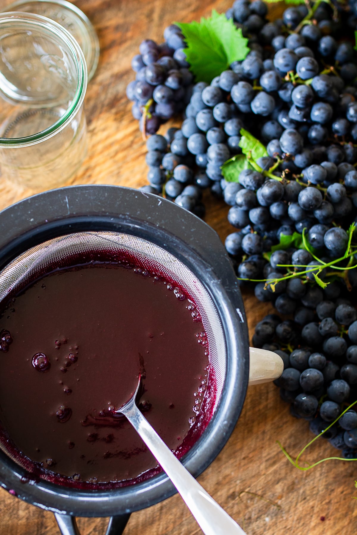 Fresh Concord grape juice being strained through a fine mesh strainer before reducing into concentrate